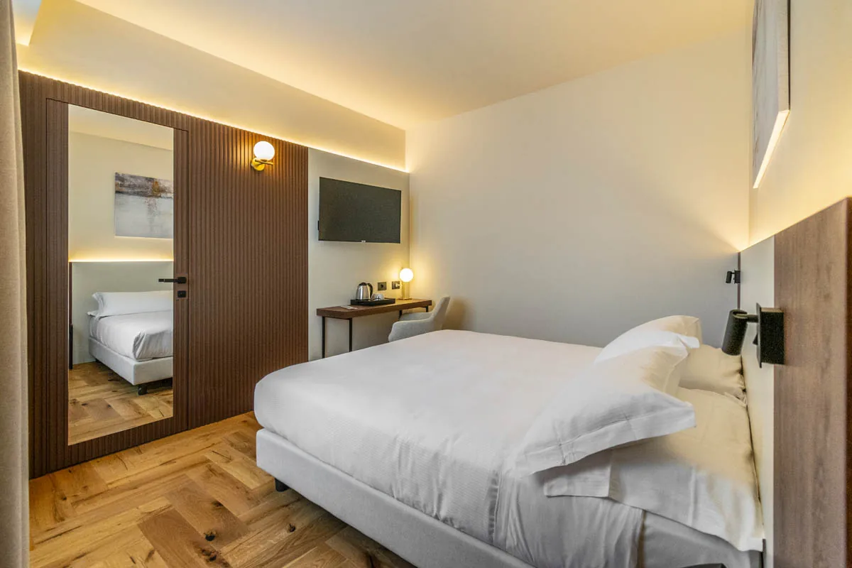 camera Deluxe con letto matrimoniale, scrivania, televisore e parete a specchio