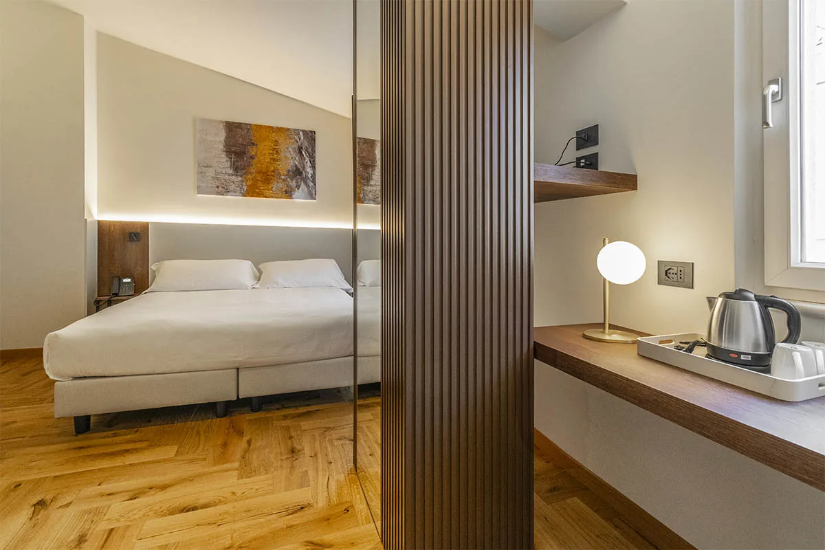 junior suite con letto matrimoniale, specchio divisorio e angolo scrivania