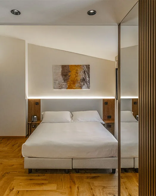 junior suite con letto matrimoniale, quadro sopra la testata e parete a specchio