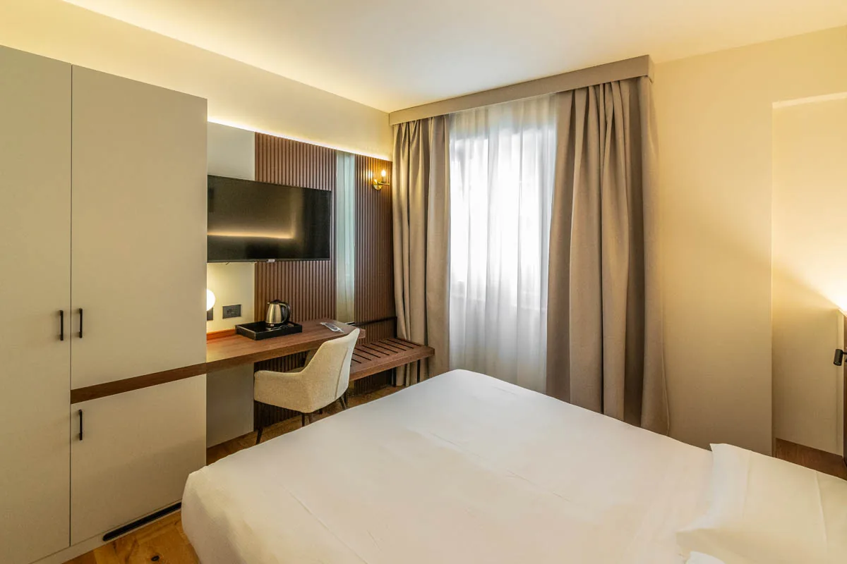camera Standard con letto matrimoniale, armadio, scrivania e finestra con tende